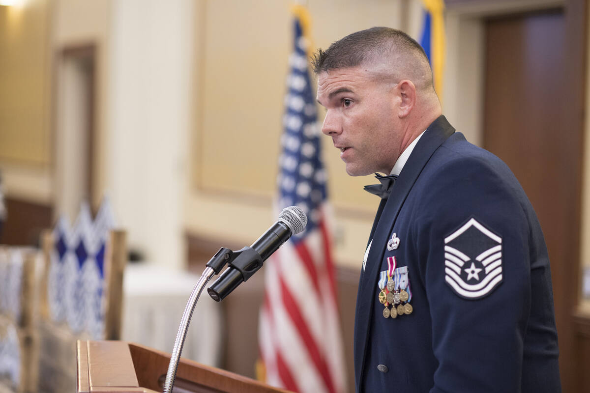Brian Fisher, retired USAF Senior Master Sergeant, speaking at podium in dress blues with medals
